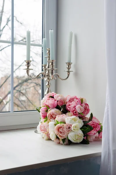 Ramo de flores blancas y rosadas con velas cerca de la ventana . — Foto de Stock