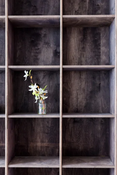 Wooden bookshelf with bouquet of flowers, industrial interior style. — Stock Photo, Image