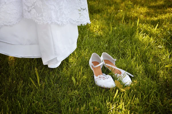 Wedding dress hanging on a tree in the park and white ladies shoes — Stock Photo, Image