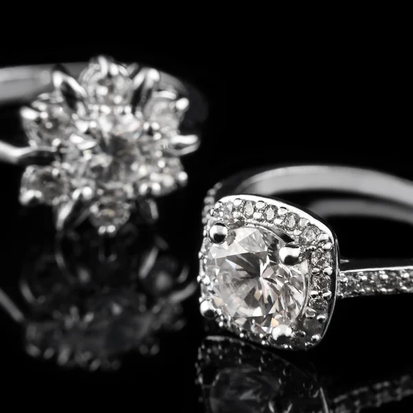 Gioielli di lusso. Anelli di fidanzamento in oro bianco o argento con diamanti primo piano su sfondo in vetro nero. Focus selettivo . — Foto Stock