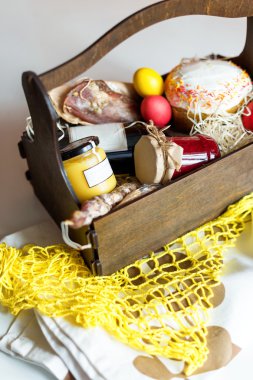 Bir sepet kek, kırmızı şarap, hamon ve veya düzensiz ve kuru tütsülenmiş sosis beyaz arka plan üzerinde renkli Paskalya yumurtaları.