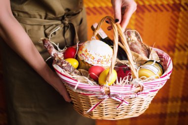 Sepet renkli yumurta, pasta, kırmızı şarap, hamon ve tutan eller veya sarsıntılı ve kuru tütsülenmiş sosis. Paskalya kutlamaları için ayarla gıda Hediyelik.