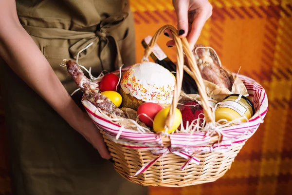 Sepet renkli yumurta, pasta, kırmızı şarap, hamon ve tutan eller veya sarsıntılı ve kuru tütsülenmiş sosis. Paskalya kutlamaları için ayarla gıda Hediyelik.