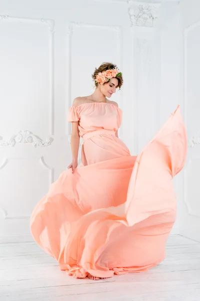 Беременная женщина танцует в розовом вечернем платье, летит на ветру. Размахивая тканями, модный снимок . — стоковое фото