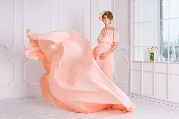 Mulher grávida dançando em vestido de noite rosa voando no vento. Tecido ondulado, tiro de moda . — Fotografia de Stock