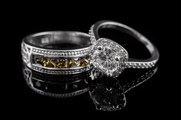 Anillos de compromiso en plata o oro blanco con gemas y diamantes amarillos sobre fondo de cristal negro . —  Fotos de Stock