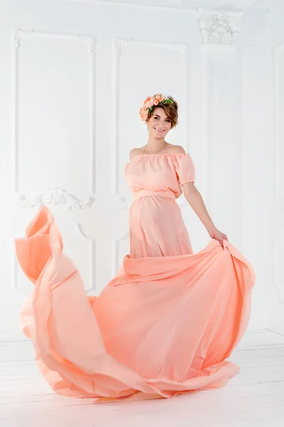 Mulher grávida dançando em vestido de noite rosa voando no vento. Tecido ondulado, tiro de moda . — Fotografia de Stock