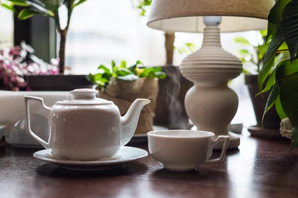 Чайник і чашка з чаєм в інтер'єрі кафе . — стокове фото