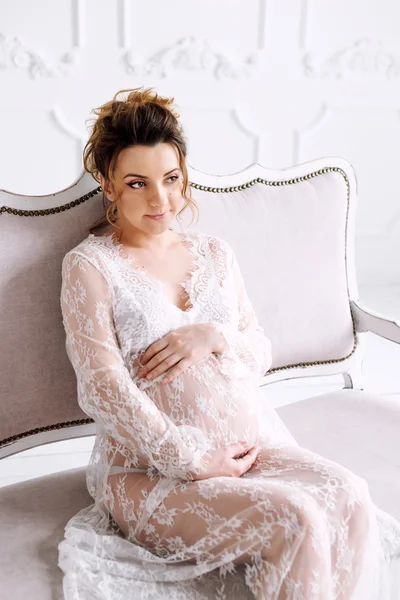 Young pregnant woman wearing lace dress in white interior. Fashion shot. — Stock Photo, Image