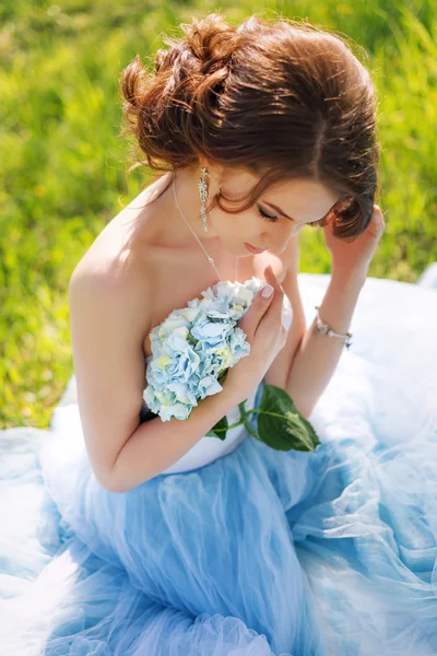Junge Braut sitzt auf dem Gras im Park — Stockfoto