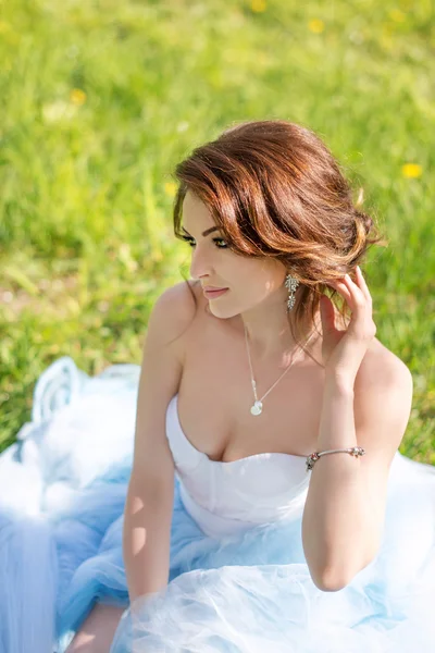Young bride sitting on the grass in the park — Stock Photo, Image