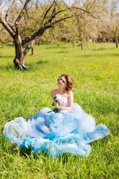 Young bride sitting on the grass in the park — Stock Photo, Image