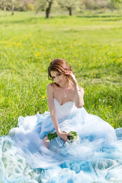 Young bride sitting on the grass in the park — Stock Photo, Image