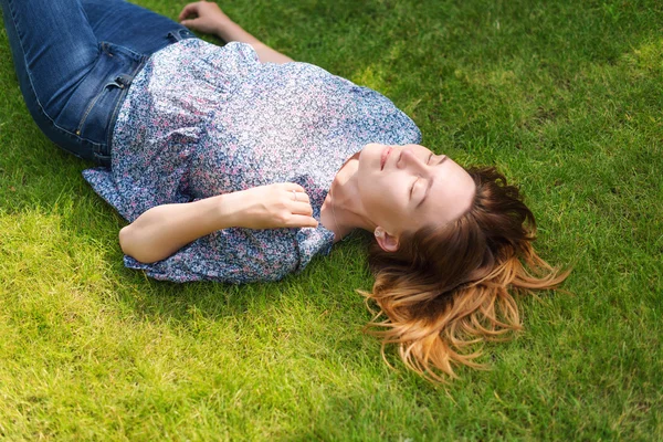 Happy woman lying down on green grass — Stock Photo, Image