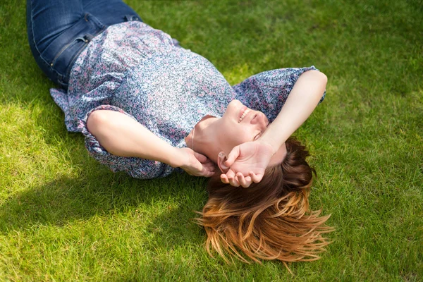 Happy woman lying down on green grass — Stock Photo, Image