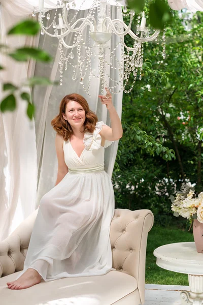 Mooie vrouw met plezier in de zomer tuin gazebo. Weelderige buiten woongedeelte met bloemen voor de viering, tea party. — Stockfoto