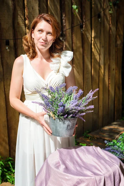 Vacker kvinna ha kul i sommarträdgården. Utomhus vardagsrum med lavendel blommor för fest, tebjudning. — Stockfoto