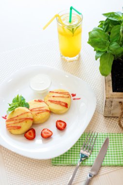 Çilek kurabiye peynirli sos, beyaz tabak ve bardak limon soğuk içecek restoranda nane yaprakları.