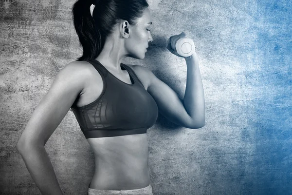 Cvičení s hmotností na pozadí betonovou zeď v tělocvičně fit žena. Koncept zdravého životního stylu. — Stock fotografie
