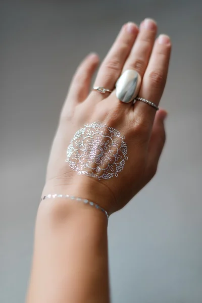 Woman hand with silver jewelry and flash tattooes in indian style. Summer beach fashion. — Stock Photo, Image