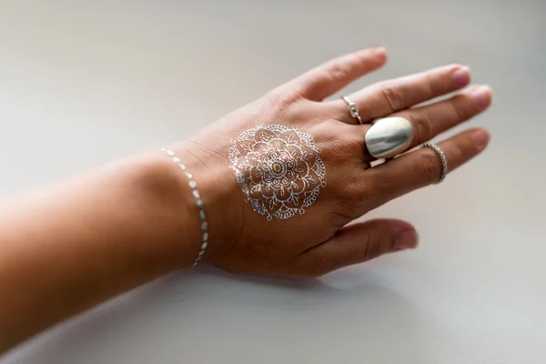 Woman hand with silver jewelry and flash tattooes in indian style. Summer beach fashion. — Stock Photo, Image