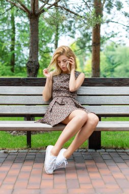 Parkta telefonda konuşurken gülümseyen güzel kadın.