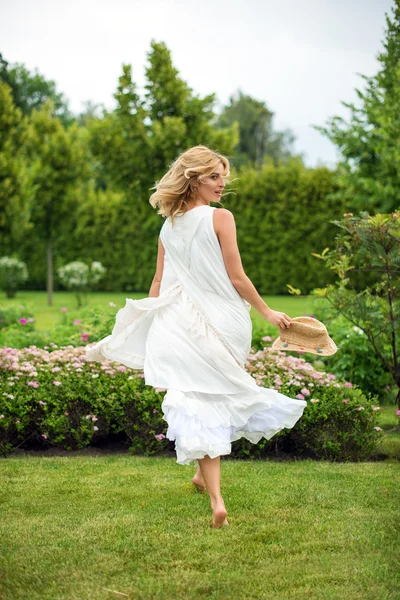 Счастливая молодая блондинка ходит босиком по зеленой траве — стоковое фото