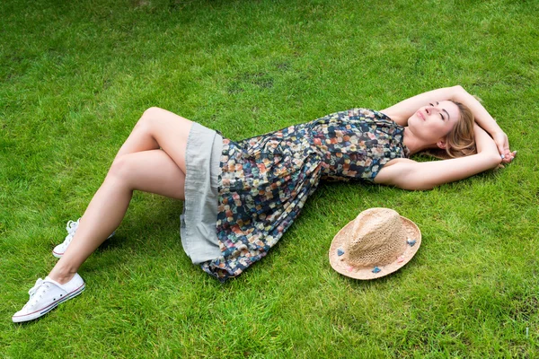 Junge Frau entspannt auf einer schönen grünen Wiese. — Stockfoto