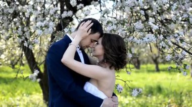 Güzel genç çift gelin ve damat kucaklayan ve çiçek açan bahçede öpüşme.