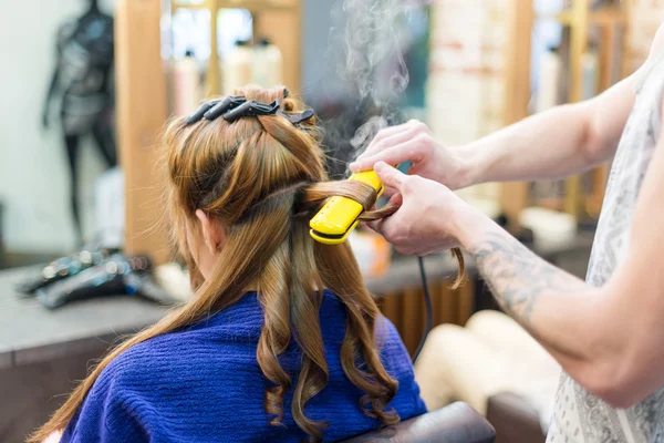 Professional hairdresser using curling iron hair curls — Stock Photo, Image