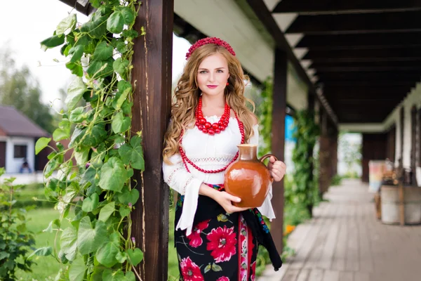 Kvinna i ukrainska traditionell folkdräkt håller en lerkruka och välkomnat gäster — Stockfoto