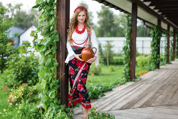 Kvinna i ukrainska traditionell folkdräkt håller en lerkruka och välkomnat gäster — Stockfoto