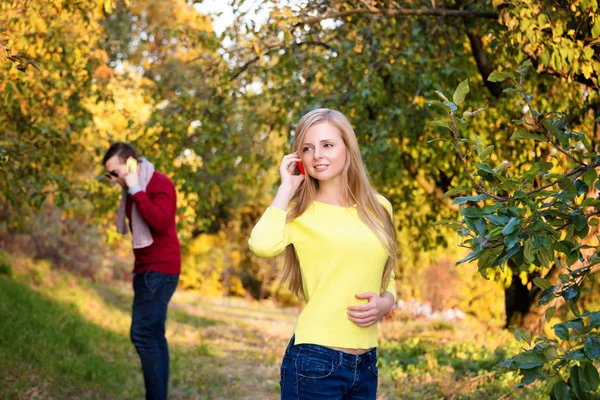 Young couple using a mobile phones. Young couple talking themselves by mobile phone. — Stock Photo, Image