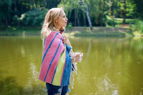 Woman wrapped in a blanket drinking tea in the forest — Stock Photo, Image