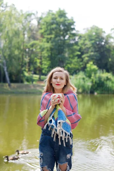 In eine Decke gehüllte Frau trinkt Tee im Wald — Stockfoto