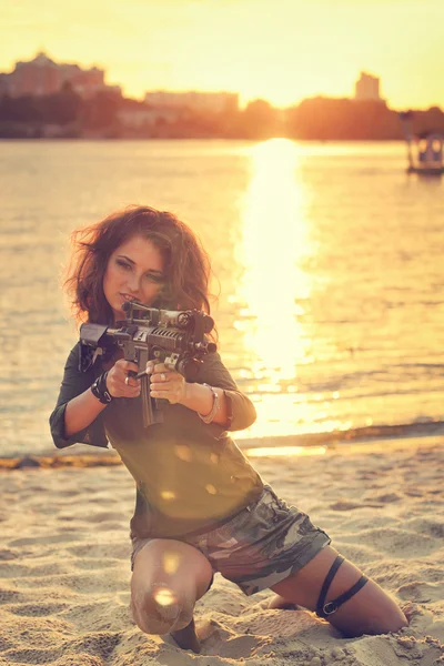 Οπλισμένοι όμορφη νεαρή γυναίκα στο καμουφλάζ με τουφέκι στην παραλία. Στρατιωτικό, στρατός και πολέμου έννοια. — Φωτογραφία Αρχείου