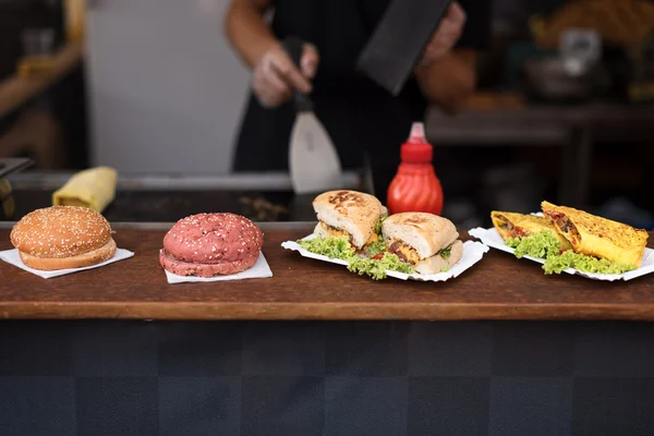 Chef haciendo hamburguesas de carne al aire libre en cocina abierta evento internacional festival de comida callejera . — Foto de Stock