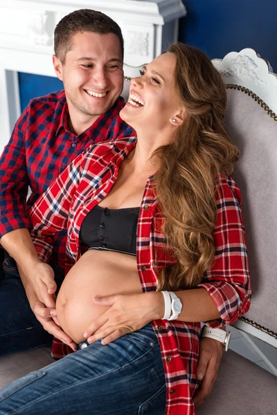 Güzel hamile çift birlikte evde kanepede rahatlatıcı. Mutlu aile, erkek ve kadın bir çocuk bekliyor. — Stok fotoğraf