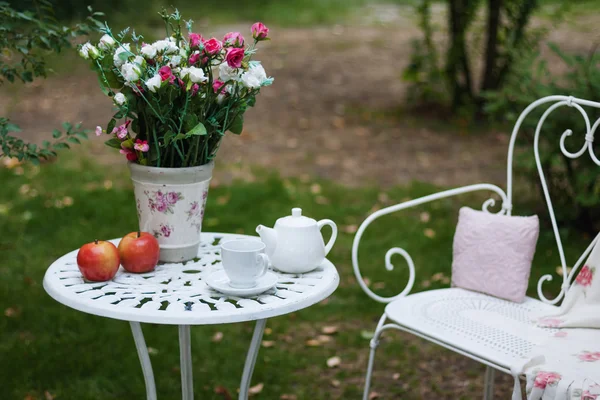 Conjunto de porcelana blanca para té o café en la mesa en el jardín sobre fondo de la naturaleza verde borrosa. Verano partido al aire libre ajuste . — Foto de Stock