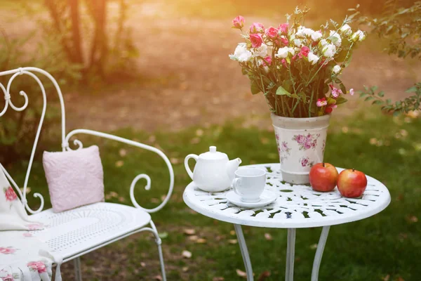 Λευκή πορσελάνη οριστεί για τσάι ή καφέ στο τραπέζι στον κήπο πάνω θαμπάδα φόντο πράσινο της φύσης. — Φωτογραφία Αρχείου