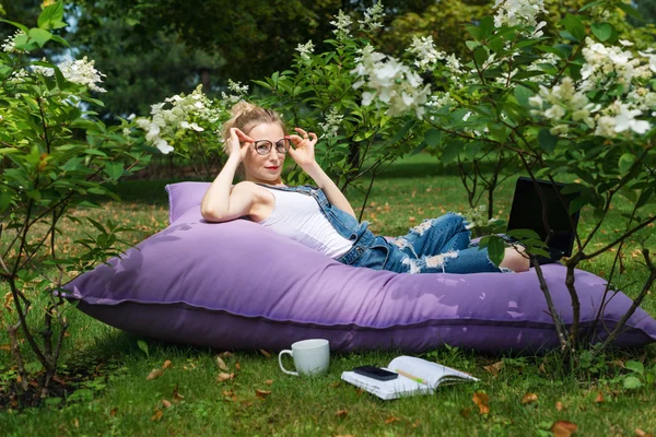 庭で働いているフリーランス。執筆、インターネットでサーフィン。公園エリアでリラックスして楽しんでいる若い女性。距離教育、フリーランスの概念. — ストック写真