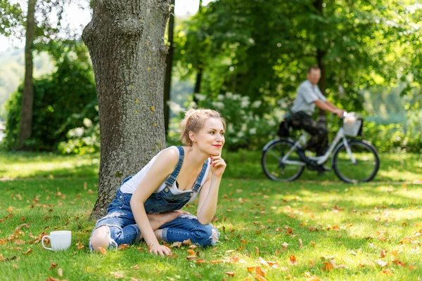 Young blonde woman drinking coffee or tea in the forest enjoying the warm weather in autumn. — Stock Photo, Image