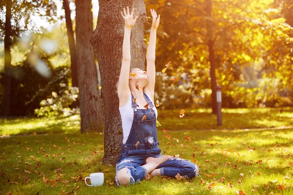 Young blonde woman drinking coffee or tea in the forest enjoying the warm weather in autumn. — Stock Photo, Image