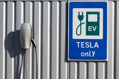 Kyiv, Ukrayna - 17 Ekim 2020: Tesla Araç Şarj Sadece gri bir çite karşı şarj istasyonu yakınında işaret.
