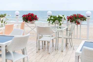 Terasta denize bakan bir restoranın boş masaları ve sandalyeleri. Deniz manzaralı bir kafe. Seaview ile yemek yemek için güzel bir yer. Seçici odak