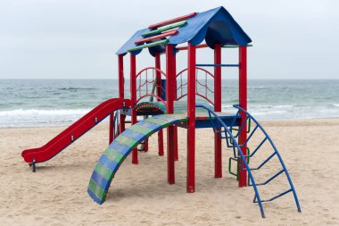 Sahilde aktif oyunlar için bir çocuk oyun alanı. Denize yakın bir parkta renkli, boş bir oyun alanı. Kamusal alanların iyileştirilmesi