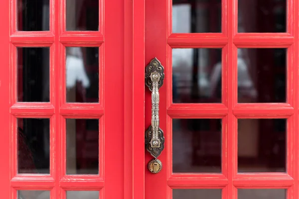 Starožitná kovová klika na červených dřevěných dveřích — Stock fotografie