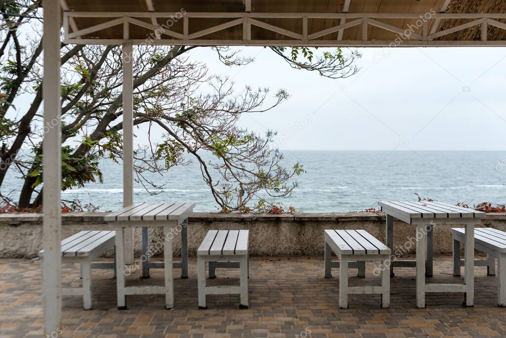 Empty tables and chairs of a restaurant on a terrace overlooking the sea. Cafe with sea view. Nice place to eat with seaview. Selective focus