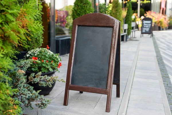 Signboard on the street. Empty menu board stand. Restaurant sidewalk chalkboard sign board. Freestanding A-frame blackboard near outdoor cafe. Copyspace for text, selective focus.