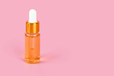 Deri özlü yağ damlası şişesi pembe arka planda. Sıvı serumu, yüz derisi için vitaminler. Kolajenle yaşlanma önleyici serum ve damlatıcıyla cam şişede peptid. Estetik, minimalizm